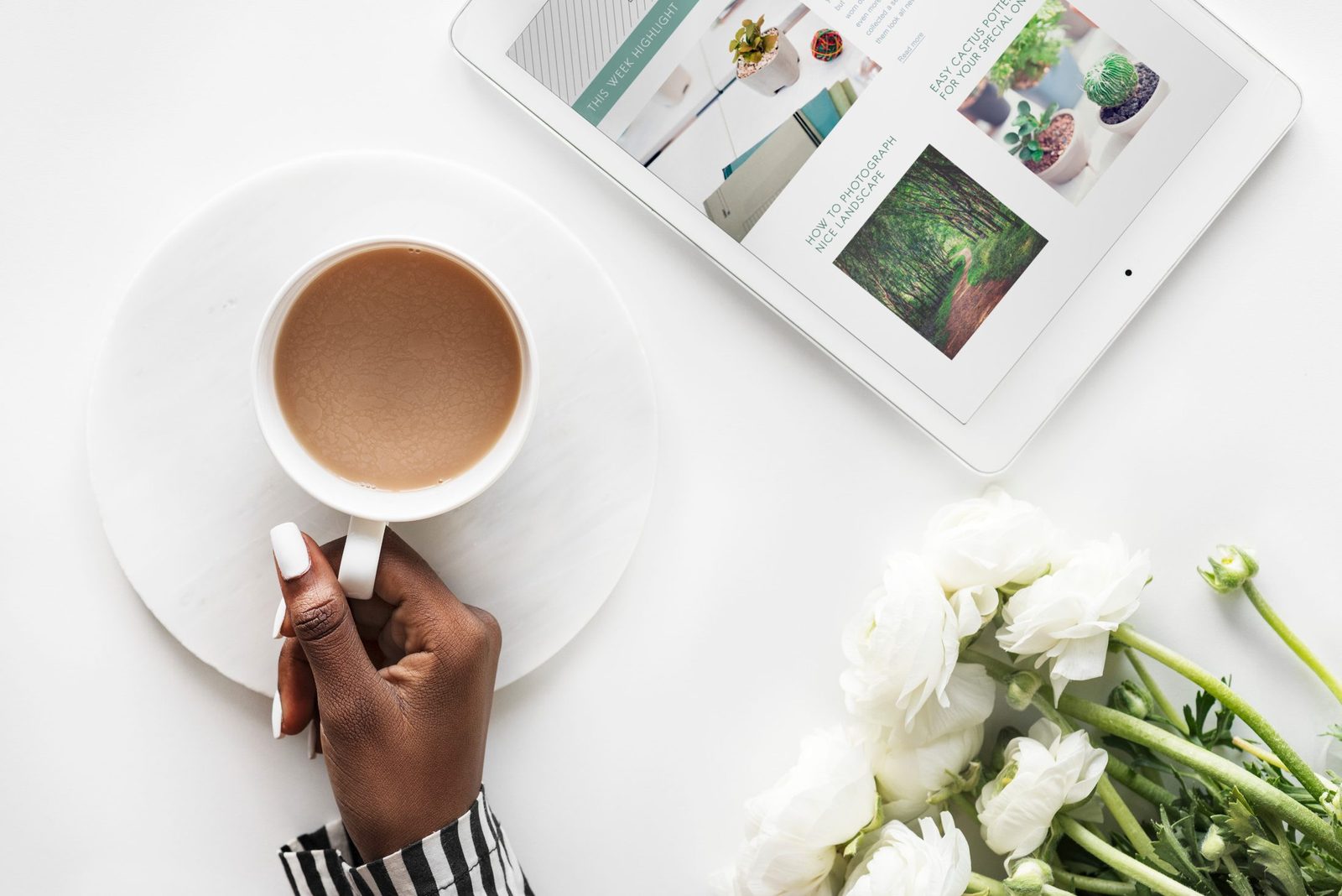 A cup of coffee beside a tablet open to an article